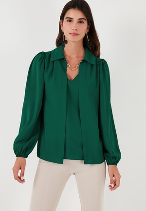 Green blouse with a pointed collar, long puff sleeves, and a V-neckline. Smooth fabric, featuring a relaxed fit and subtle pleat detail.