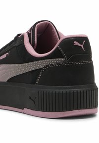 Musta mokkanahkakengät vaaleanpunaisilla yksityiskohdilla, joissa on teksturoitu alusta, ommeltu koristelu ja merkittävä Puma-logo sivussa.