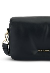 Zwarte leren schoudertas met een gladde textuur, gouden hardware en reliëf logo-detail. Voorzien van een verstelbare schouderband en een strakke rechthoekige vorm.