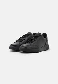 Sneaker nere in pelle con texture liscia, punta tonda, lacci piatti e suola in gomma a contrasto. Design minimalista senza loghi visibili.