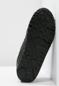 Černá podrážka tenisky Nike s vzorkem a embosovaným logem "NIKE" na spodní straně, umístěná na bílé ploše.