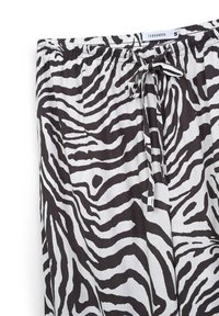Pantaloni del pigiama a strisce zebrate in bianco e nero con vita elasticizzata e cordoncino. Tessuto morbido, leggero e design casual.