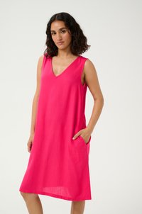 Robe sans manches rose avec un décolleté en V, fabriqu�ée en tissu léger. Elle présente des poches latérales et une coupe fluide qui tombe au-dessus des genoux.