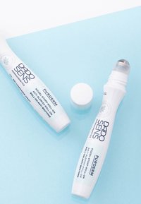 Dado Sens Purderm anti-blemish roll-on. White tube with a curved design, silver rolling ball applicator, and blue background.