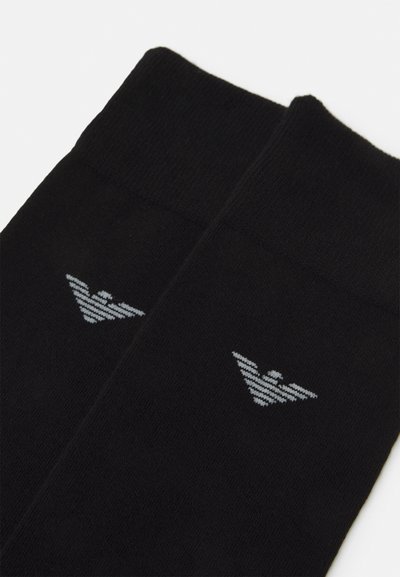 Chaussettes noires en tissu doux avec un logo gris et des rayures de chaque côté. Le design comprend un haut côtelé.