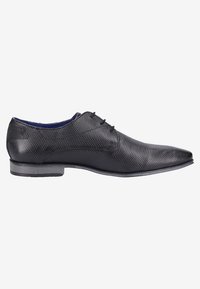 Chaussure habillée pour homme en cuir noir texturé, avec un bout pointu, un petit talon et des lacets noirs, présentée en profil latéral sur fond blanc.