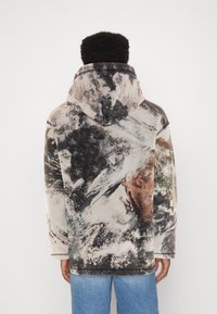 Hoodie van zachte stof, met een meerkleurig abstract aardepatroon in bruin, zwart en wit. Ontspannen pasvorm.