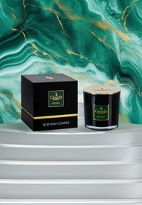 Bougie parfumée en verre noir avec un couvercle doré, montée à côté d'une boîte noire avec du texte doré. L'arrière-plan est orné de motifs en marbre vert.