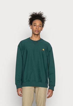 Sweatshirt de algodão verde-escuro com gola redonda, punhos canelados e um pequeno logotipo amarelo e vermelho no peito. Textura suave, corte descontraído.