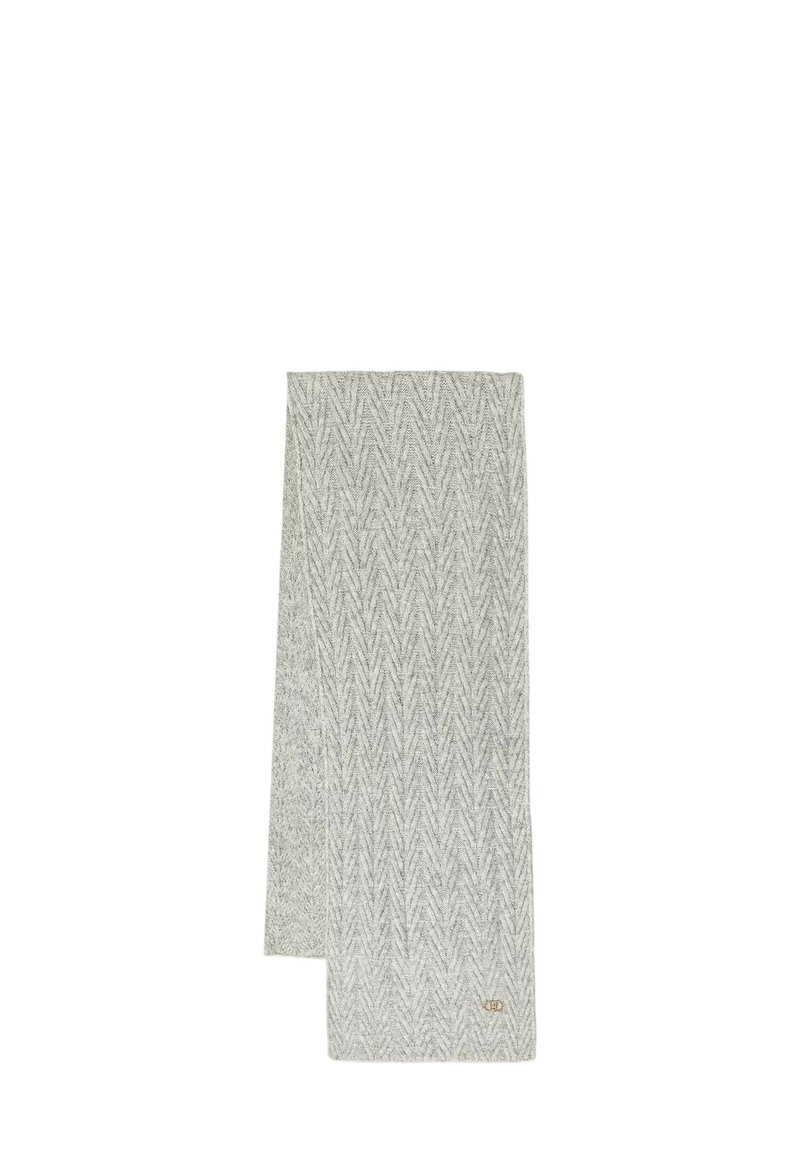 Sciarpa lavorata a maglia color grigio chiaro con motivo a zigzag a rilievo e un piccolo emblema dorato vicino a un'estremità, distesa su uno sfondo bianco.