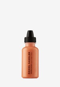 Peskefarget flytende blush i en gjennomsiktig flaske med svart skrukork. Viser merkevarenavnet og produktbeskrivelsen i fet tekst.