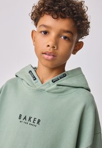 Világoszöld kapucnis pulóver puha anyagból, nagy, fekete "BAKER" logóval, dupla rétegű kapucnival és bordázott részletekkel.