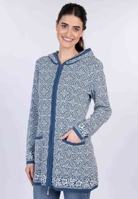 Blau gemusterter Reißverschluss-Hoodie mit floralen und schneeflockenförmigen Designs, ausgestattet mit Fronttaschen und kontrastierenden blauen Abschlüssen entlang der Kanten.