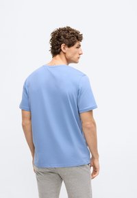 T-shirt de algodão azul claro com mangas curtas e decote redondo, exibida de costas. Corte reto com textura suave.