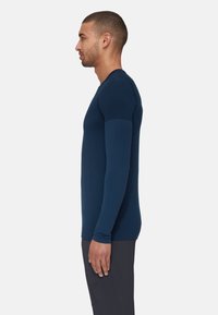 Långärmad åtsittande topp i mörkblått, tillverkad av ett slätt tyg. Har en rund halsringning och sömlösa axlar för komfort.