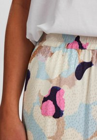 Tessuto fluido e leggero con un motivo astratto multicolore che presenta tonalità di blu, rosa e marrone. Vita elastica con una sottile trama.