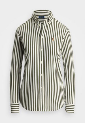 Pik kontinugae varrukatega särk, millel on rohelised ja valged vertikaalsed triibud, nööpidega krae ning vasakul rinnaosal tikandiga logo. Omab klassikalisi nööpidega esiosasi.