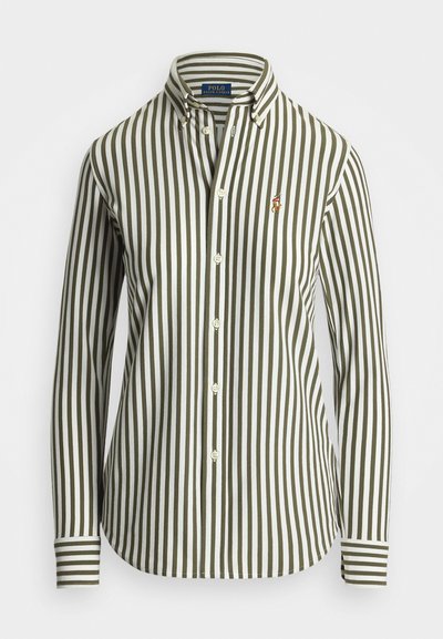 Majica z dolgimi rokavi z zelenimi in belimi navpičnimi črtami, ovratnikom na gumbe in izvezenim logotipom na levem prsnem delu. Ima klasično zapenjanje spredaj.