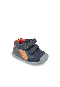 Zapato para niño pequeño en color azul marino con tiras de velcro, detalles en color marrón y suela de goma. Presenta lados perforados y un diseño de punta redondeada.