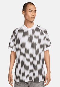 Mannen polo shirt in het wit met een zwart abstract patroon, voorzien van een klassieke kraag, korte mouwen en een Nike-logo op de borst.