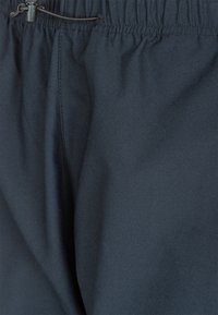 Svarta träningsbyxor med elastisk midja och justerbar dragsko. Slät textur och lätt glans med platta sömmar.