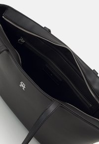 Schwarze Lederhandtasche mit glatter Textur, mit Reißverschluss versehenen Innenfächern und einem silbernen Logoakzent. Minimalistisches Design mit stabilen Griffen.