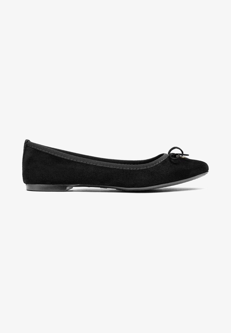 Chaussure ballerine plate en daim noir avec un petit nœud sur l’avant arrondi et un talon plat bas, vue de profil sur fond blanc.