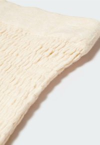 Krmově zbarvená pletená vlněná látka s texturovaným, mírně vyvýšeným vzorem, s jemným a útulným vzhledem a hladkými okraji.