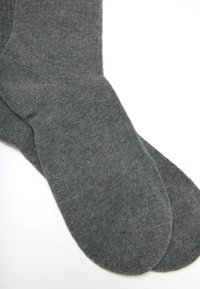 Calze grigie con una texture liscia, bordo a coste e punta rinforzata. Realizzate in tessuto morbido, presentano un colore uniforme senza fantasie.