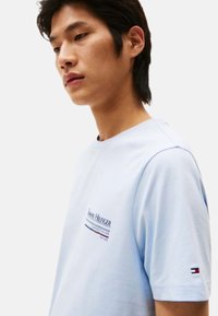 Camiseta de algodón de color azul claro con cuello redondo, mangas cortas y un estampado de logo en el pecho. Incluye un pequeño acento de logo en la manga.