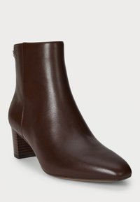 Bottines en cuir marron avec un bout pointu, un petit talon carré et une texture lisse. Dotées d'une fermeture éclair sur le côté pour un enfilage facile.