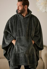 Grauer Strick-Poncho mit Kapuze, oversized Design, strukturiertes Material und einer Fronttasche. Weich und warm für lässige Outfits.