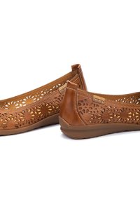 Bailarinas de cuero marrón con patrones florales recortados, lados texturizados y suela de goma flexible. Marca visible en la parte superior.