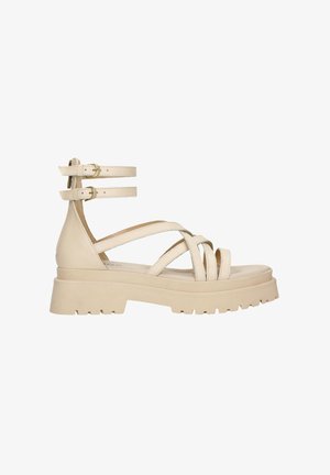Béžové kožené sandály s dvojitými přezkami na kotníku, křížovým designem a masivní platformou se zdrsněným povrchem.