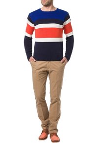 Pull tricot rayé bleu marine et bleu avec des rayures horizontales rouges et blanches, associé à un pantalon beige et des chaussures bateau orange. Coupe décontractée.