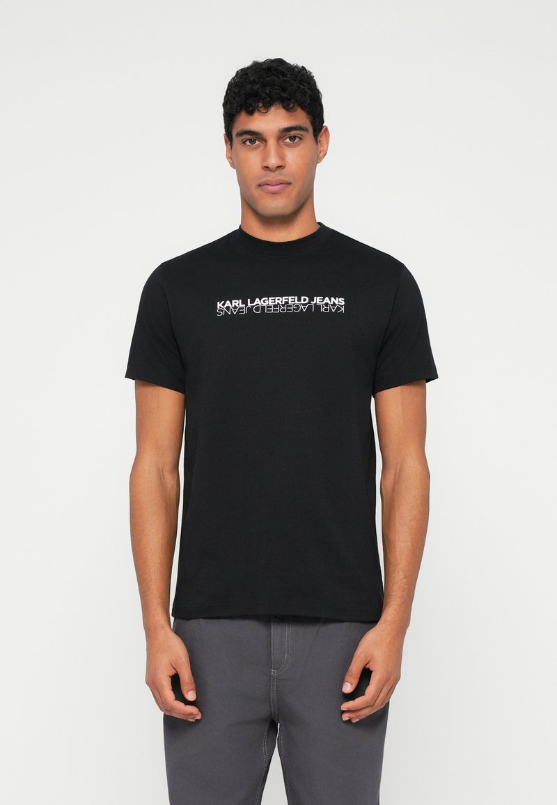 Melnas kokvilnas T-krekls ar uzrakstu "KARL LAGERFELD JEANS", kas drukāts baltā krāsā krūtīs. Klasiķa apaļa kakla forma un īsas piedurknes.