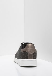 Ciemnobrązowy sneaker z wzorem gwiazd, miękka tekstylna cholewka, matowometaliczny obcas, biały gumowy spód oraz czarne wnętrze.