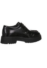 Mustat nahkaiset nauhattomat kengät kiiltävällä pinnalla, pyöreällä varvaskohdalla ja paksulla mustalla kumipohjalla, jossa on kuvioitu pinta.