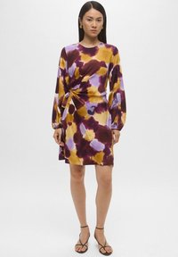 Abito a maniche corte con nodo frontale, caratterizzato da un motivo tie-dye in viola, giallo e bordeaux, realizzato in tessuto morbido.