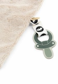 Manta de bebé suave beige con un juguete chupete verde sujeto por una correa blanca con siluetas de animales en negro.