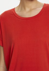 Red short-sleeved top with a round neckline, made from a smooth, lightweight fabric. Simple design, no patterns or embellishments.