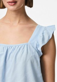 Top senza maniche di un blu chiaro, con scollatura quadrata, caratterizzato da dettagli arricciati sulle spalle e tessuto testurizzato, raccolto sul petto.