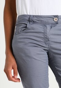 Grijze broek van een katoenmix met een gladde textuur. Voorzien van een knoopsluiting, steekzakken aan de voorkant en zichtbare stiksel details.