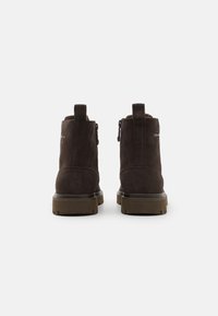 Stivaletti alla caviglia in suede marrone con chiusura a zip, linguette per il trasporto e suole in gomma. Il design semplice mette in risalto la texture liscia e il colore tenue.