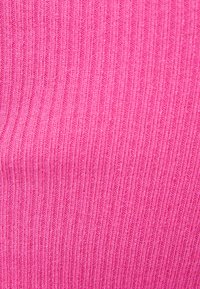 Ribbadt tyg i en livlig rosa färg, med en strukturerad yta med vertikala linjer. Mjukt, elastiskt material som är lämpligt för olika klädesplagg.