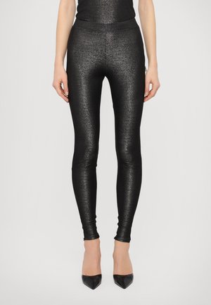Black metallic leggings with a slim fit, smooth texture, high waist, and a shiny finish, paired with black pointed-toe heels.