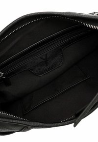 Interno di una borsa in pelle nera con una texture morbida, dotata di una tasca con zip e di un scomparto laterale, foderata in tessuto nero.