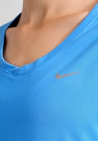 Ljusblå idrottströja av mjukt tyg med v-ringning och en liten silvrig Nike-logotyp på bröstet.