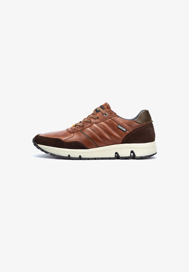 Sneaker en cuir marron avec des accents en daim, des panneaux latéraux texturés, des œillets en métal et une semelle en caoutchouc blanche. Présente un design bas profil.