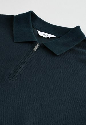Navy polo shirt with a zippered collar. Made from textured fabric, featuring a stitched label on the inside. Clean design, lightweight look.